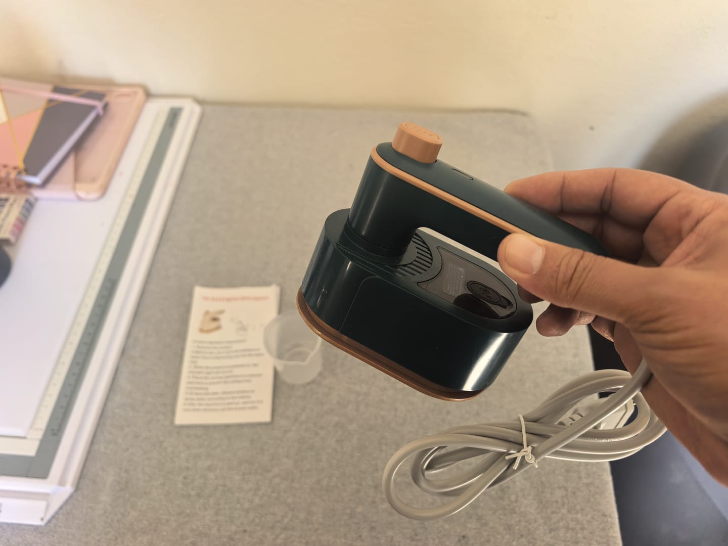 Compact green mini iron held by its rotating handle