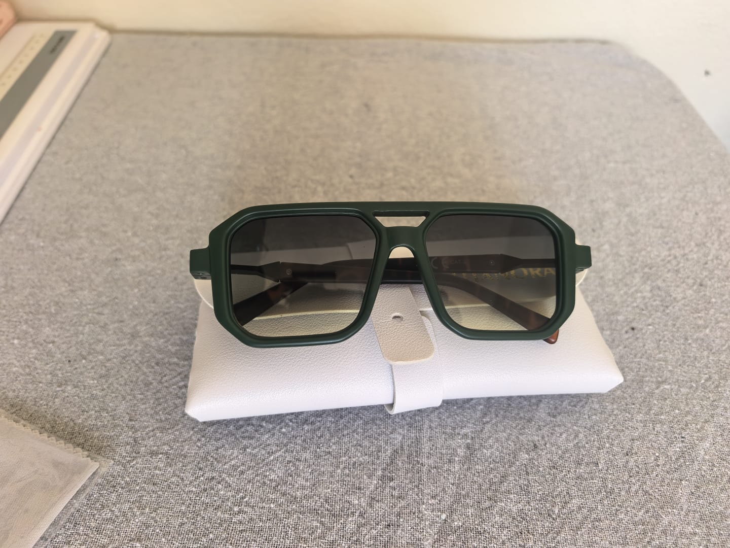 Green square-frame Titanora sunglasses shown with protective case